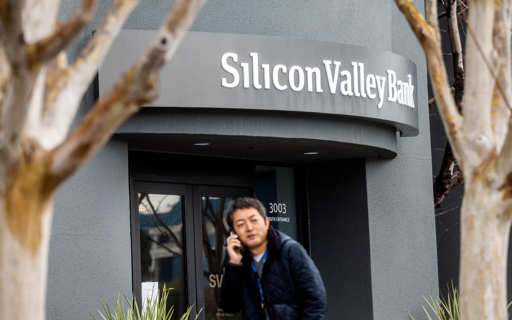 A pedestrian speaks on a mobile telephone as he walks past Silicon Valley Bank’s headquarters in Santa Clara, California on March 10, 2023. - US authorities swooped in and seized the assets of SVB, a key lender to US startups since the 1980s, after a run on deposits made it no longer tenable for the medium-sized bank to stay afloat on its own. (Photo by NOAH BERGER / AFP)