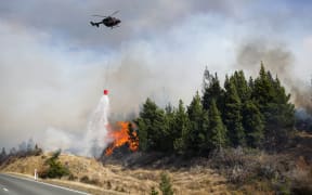 A helicopter drops water on a fire near lake Pukaki. 31 August 2020