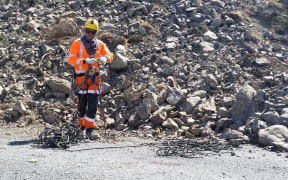 A member of an abseiling crew tidies his rope after descending a large landslide south of Kaikoura.