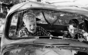 Two boys playing in wrecked car, 1957, North Island, by Eric Lee-Johnson.