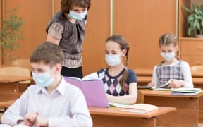 school children with protection masks against flu virus at lesson in classroom