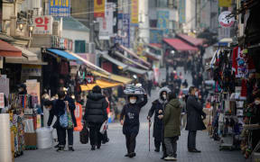 A restaurant worker carries a tray of food through Namdaemun market in Seoul on 11 December 2020.