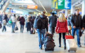 People with suitcases at airport (stock photo).