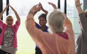 Happy active senior women exercising, stretching arms overhead in exercise class. (Photo by CAIA IMAGE/SCIENCE PHOTO LIBRARY / NEW / Science Photo Library via AFP)