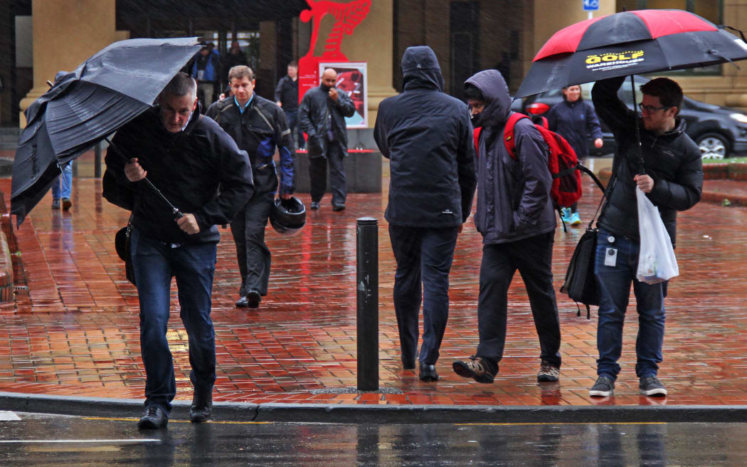 Commuters battle the horizontal wind and rain leaving Wellington Train Station.