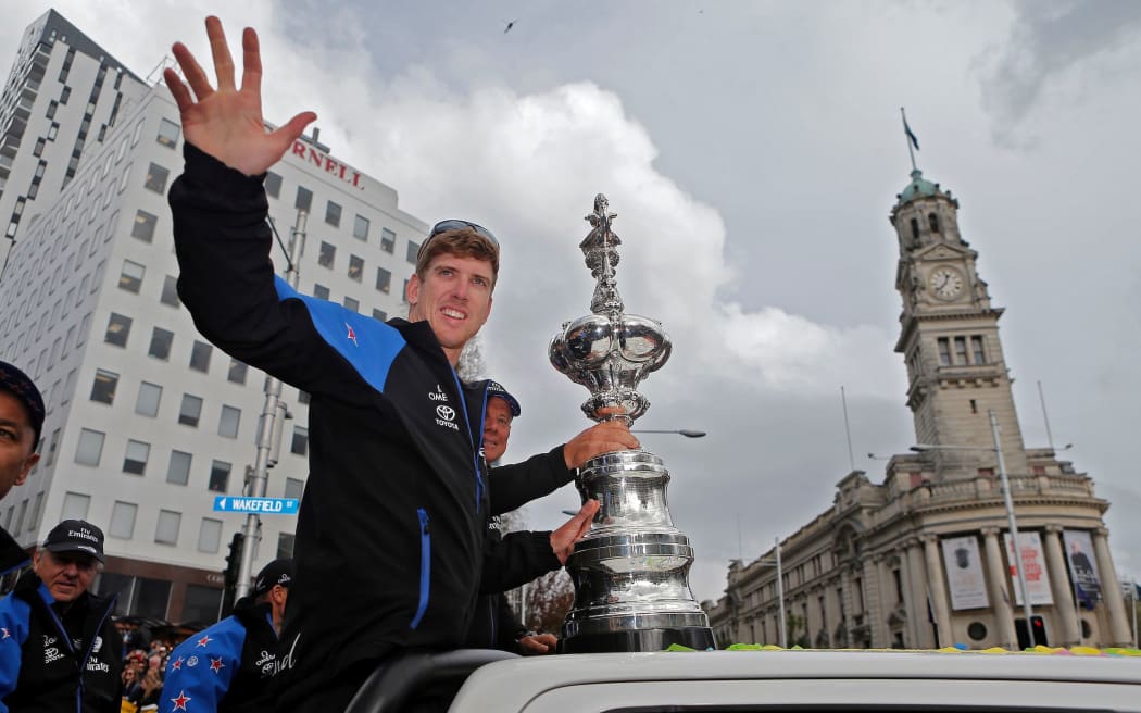 Peter Burling waves to the crowd at the America's Cup parade in central Auckland.