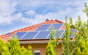 44317184 - solar panel cells on the roof of a new house agains blue sky.