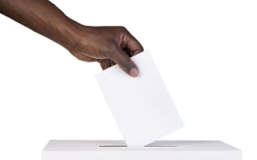 Ballot box with person casting vote on blank voting slip