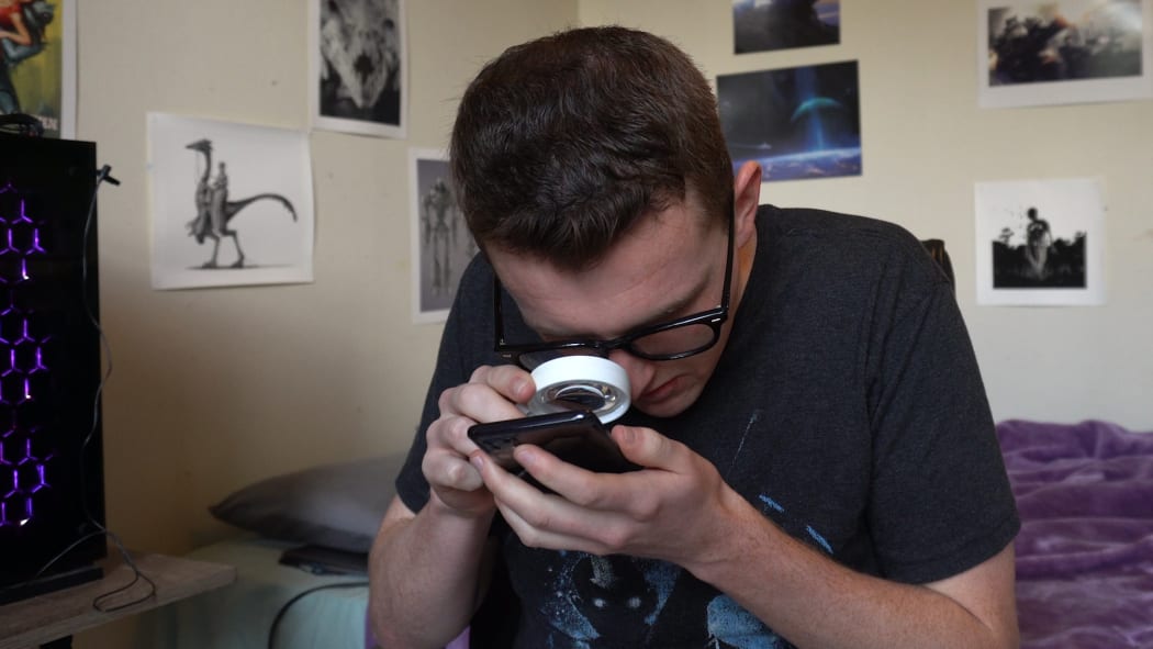 Josh Davies uses his magnifying glass to check a message.