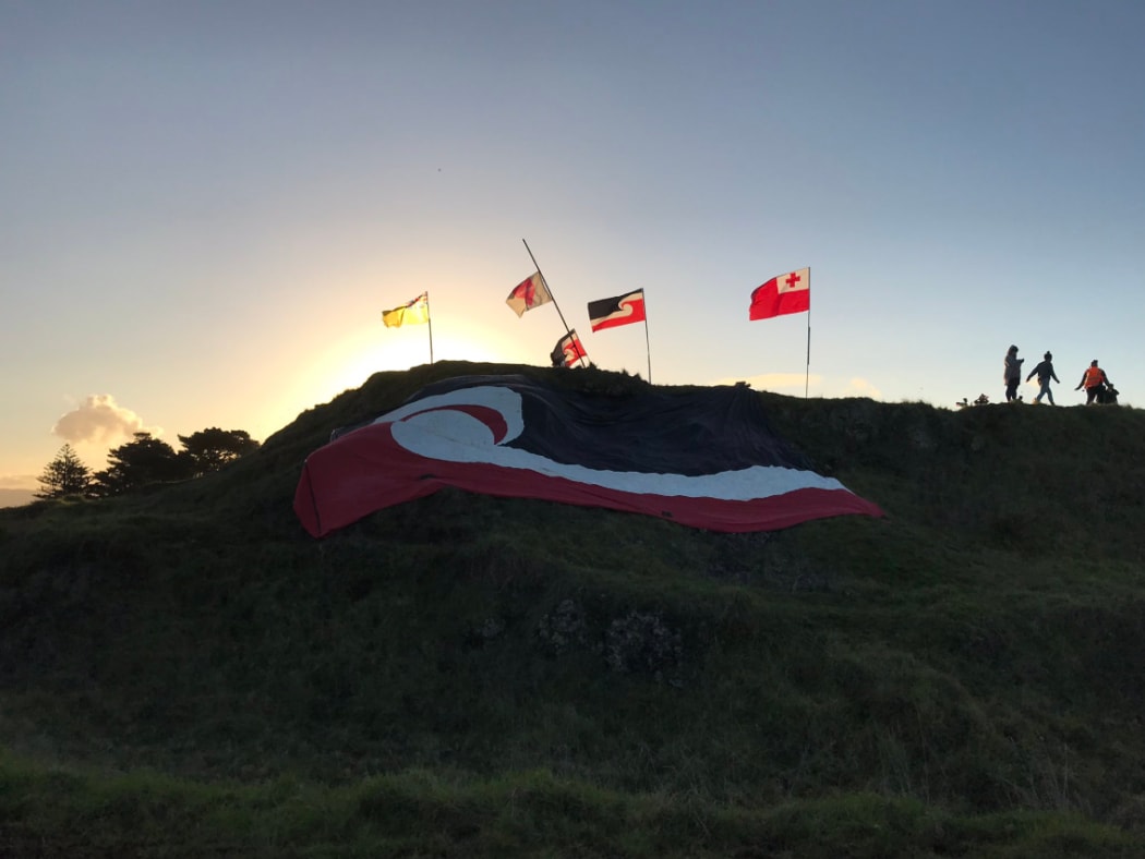 The tino rangatiratanga flag is seen at Ihumātao as the day draws to an end for protesters on the land on Friday, 26 July.