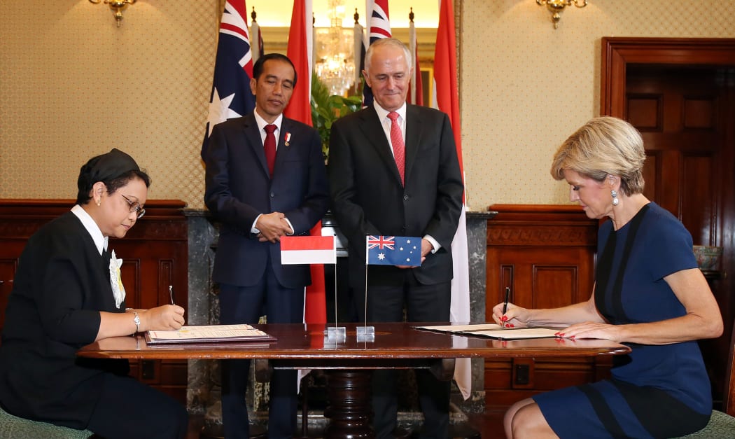 Australian Minister for Foreign Affairs Julie Bishop (R) her Indonesian counterpart Retno Marsudi (L) sign official papers during a signing ceremony between the two countries as Indonesian President Joko Widodo (2nd L) and Australian Prime Minister Malcolm Turnbull look on.