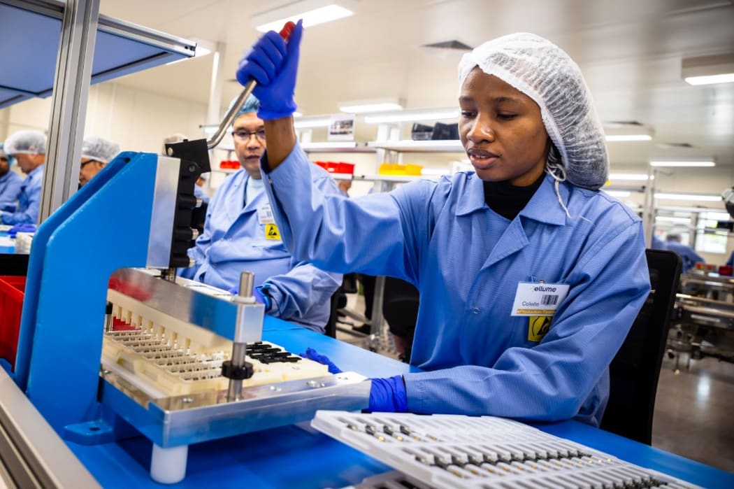 In this picture taken on December 21, 2020, employees work on the production line of a COVID-19 coronavirus home test unit  at the production facility of Australian digital diagnostics company Ellume in Brisbane.