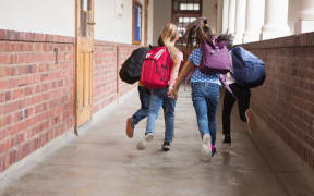 Young students running through hallway of school.