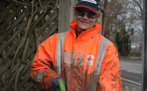 Red Cross volunteer Cathy Reed takes a break during today's clean-up in Whanganui (26 June).