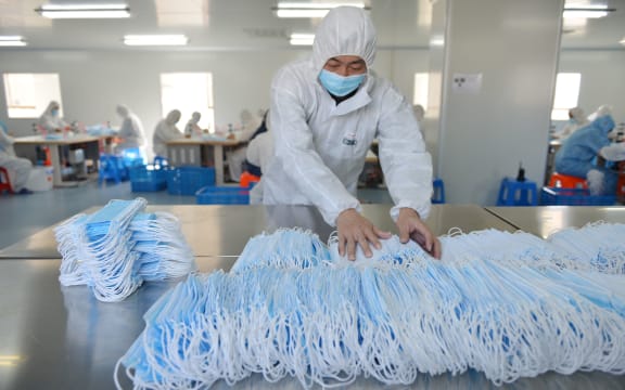 This photo taken on February 18, 2020 shows a worker sorting face masks being produced to satisfy increased demand during coronavirus outbreak, at a factory in Nanjing, in China's Jiangsu province.