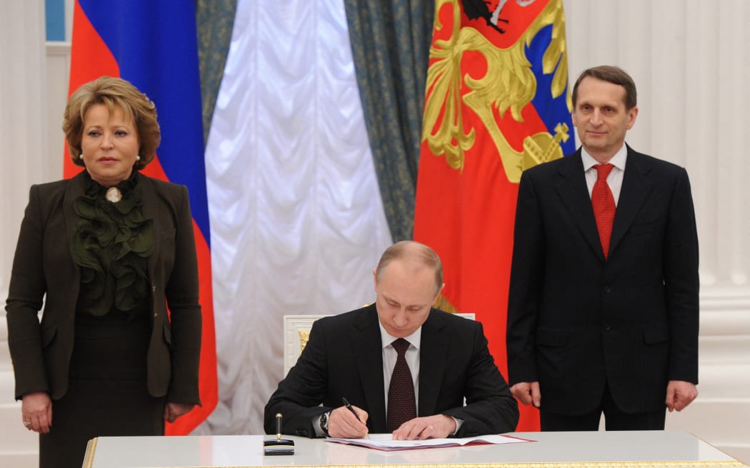 Sergey Naryshkin (R) Chairman of the State Duma and Valentina Matviyenko (L) the Chairwoman of the Federation Council of the Russian Federation stand next to the Russian President Vladimir Putin as he signs set of laws on reunification of Crimea, Sevastopol with Russia at Ekaterininsky in Kremlin, 21 March, 2014.