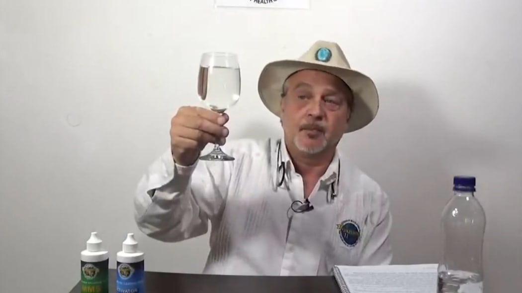Mark Grenon holds a glass containing chlorine dioxide bleach and water, which he calls Miracle Mineral Solution