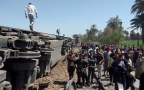 People gather at the site of a crash where two trains collided killing at least 32 people and leaving 108 injured, in city of Tahta, Egypt.