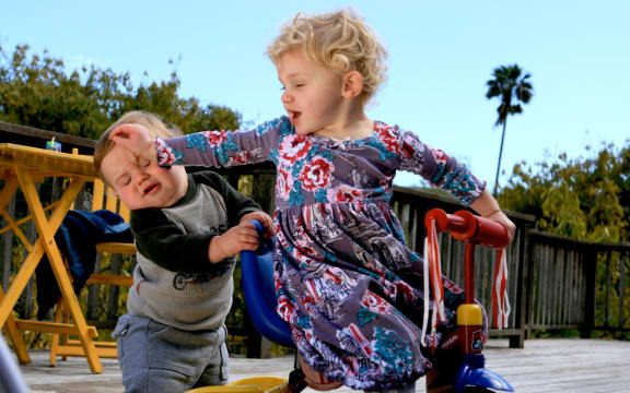 Little boy and his sister playing, pushing.