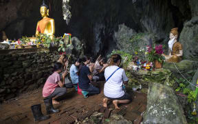 Family members pray before a shrine in Tham Luang cave area as operations continue for the 12 boys and their coach trapped at the cave in Thailand.