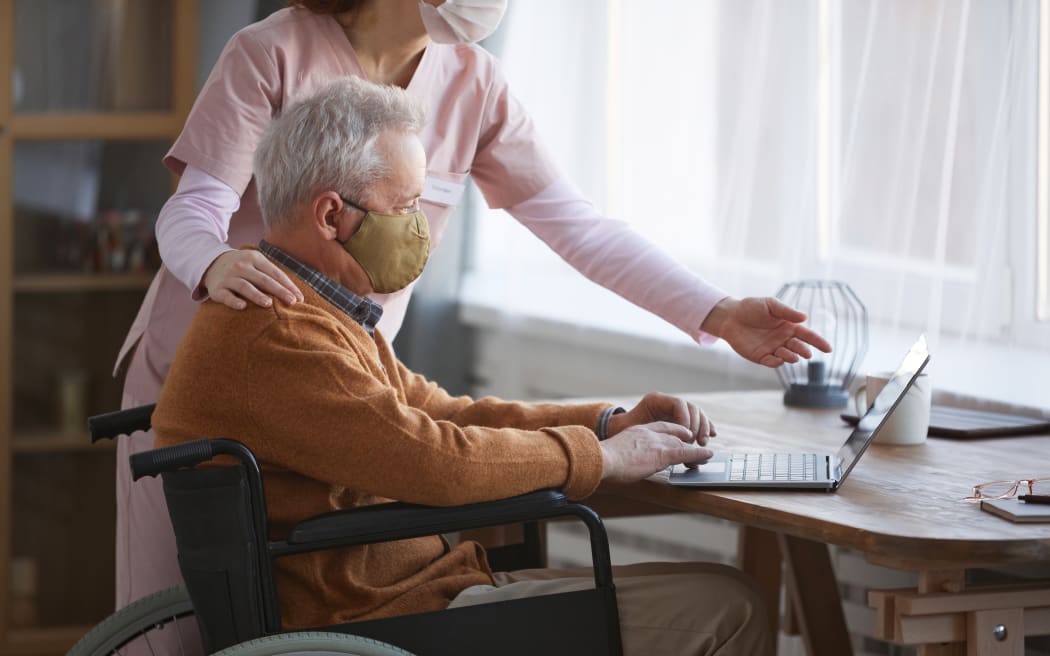 Older man in wheelchair wearing face mask.