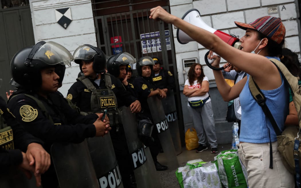 A supporter of former Peruvian President Pedro Castillo shout slogans to riot police during a protest to demand the resignation of President Dina Boluarte, Castillo's release, and Congress's closure in Lima on December 17, 2022. - Peru's embattled President Dina Boluarte said Saturday she would not step down in the face of violent protests over her predecessor's ouster as she called on lawmakers to bring forward elections as a way to quell unrest. (Photo by Lucas AGUAYO / AFP)