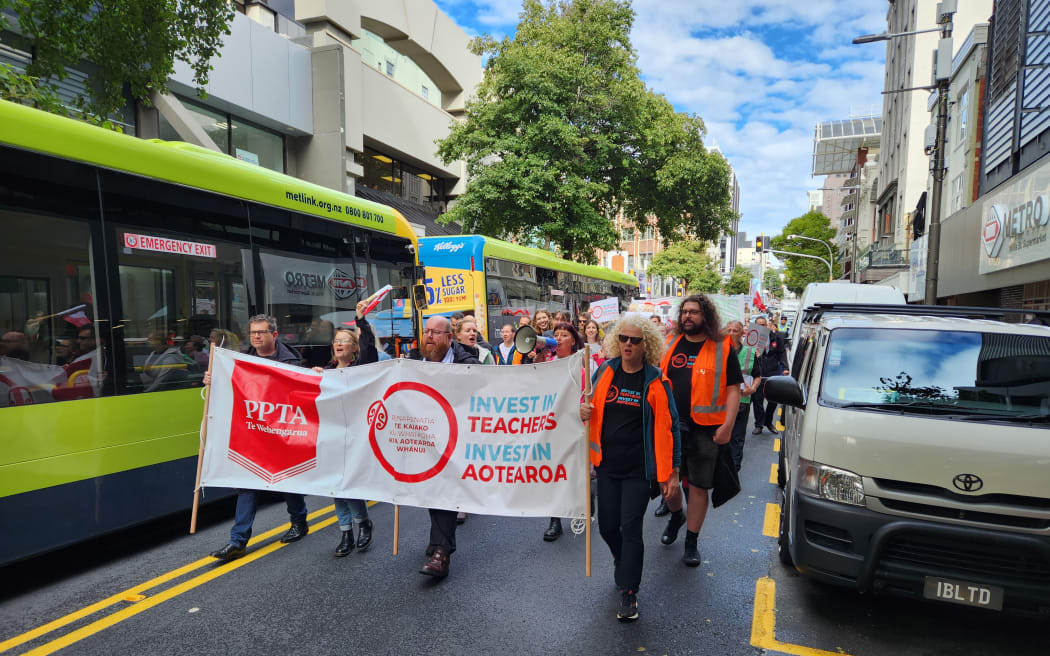 Striking teachers March through Wellington on 10 May, 2023. PPTA acting president Chris Abercrombie at centre of banner.
