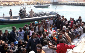 Libyan coast guards watch over illegal migrants, who had hoped to set off to Europe.