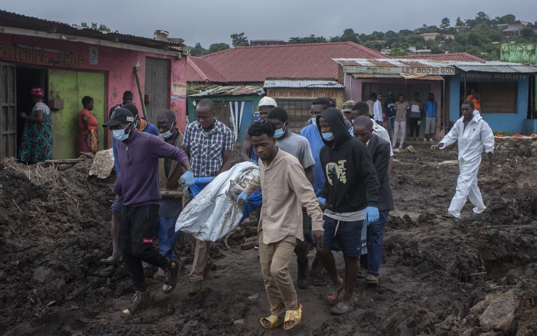 Men carry bodies from where they have been recovered to an ambulance to be taken to the morgue during search and rescue operations to recover bodies from a mudslide on Soche Hill in Blantyre, Malawi, on 17 March, 2023.