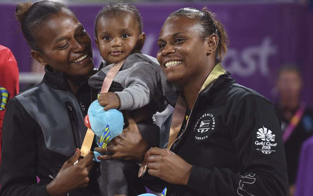 Vanuatu's Miller Pata, (L) holds her seven month-old son Tommy after receiving her bronze medal with teammate Linline Matauatu