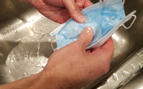 Microbiologist Richard Everts washing a disposable mask in warm water.