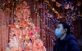 A pedestrian wearing a face mask or covering due to the COVID-19 pandemic, walks past a Christmas-themed display in a shop window on Oxford Street in central London on December 22, 2020.