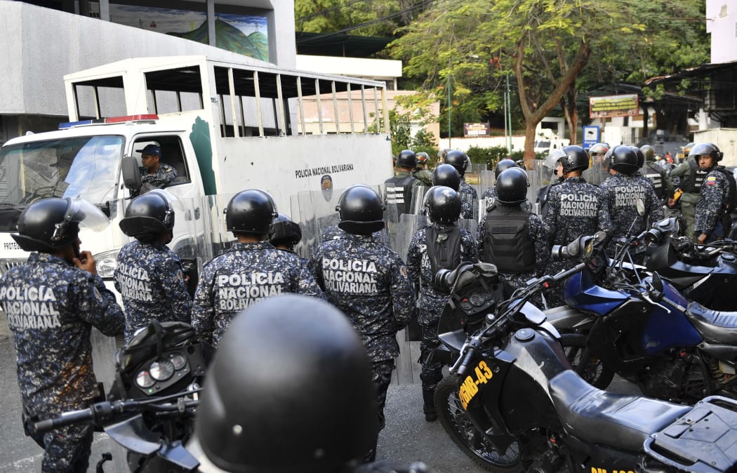 National Police officers remain outside the National Guard command post in Cotiza, in northern Caracas after a brief military uprising and amid opposition calls for mass protests.