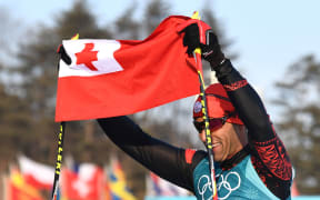 Tonga's Pita Taufatofua holds up his national flag after crossing the finish line during the men's 15km cross country freestyle at the Alpensia cross country ski centre during the Pyeongchang 2018 Winter Olympic Games on February 16, 2018 in Pyeongchang.  / AFP PHOTO / FRANCK FIFE