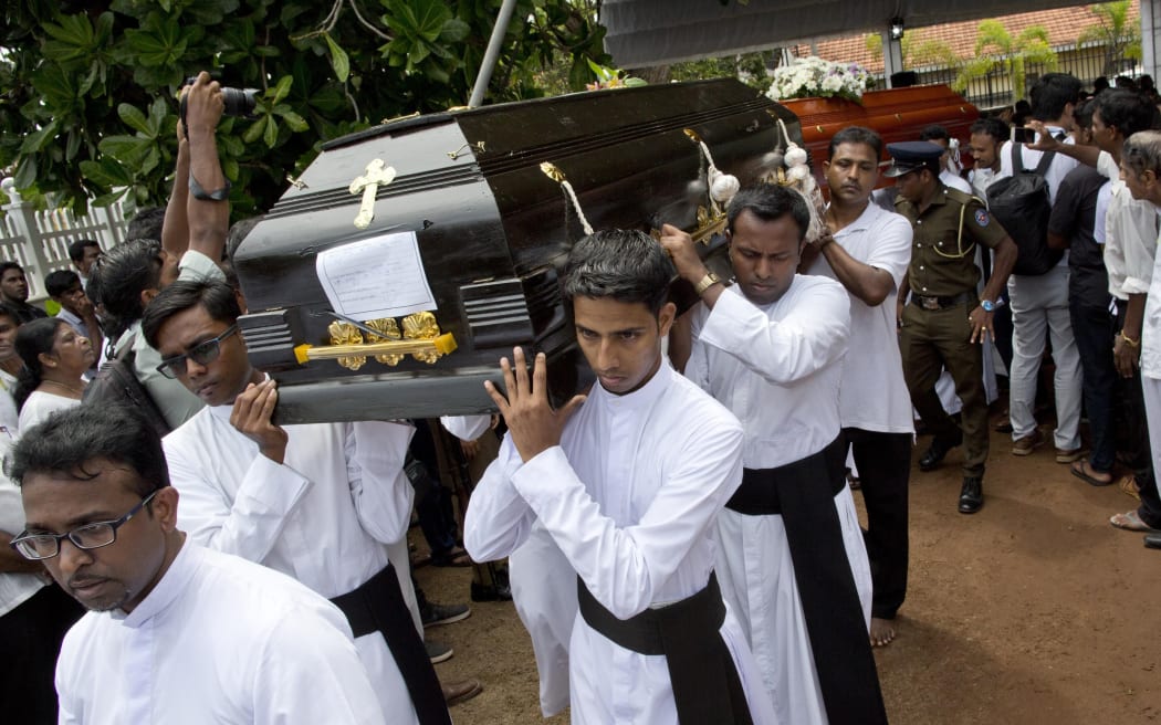 Clergymen carry coffins for burial during a funeral service for Easter Sunday bomb blast victims at St. Sebastian Church in Negombo, Sri Lanka, Tuesday, April 23, 2019.