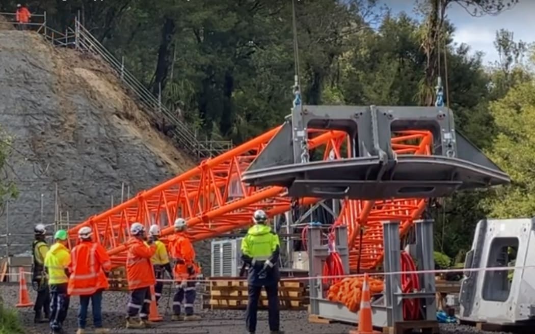 Workers watch on as a tower is put in place to hold the 1.1km cableway to take workers and materials to the site of the Mt Messenger bypass project, in North Taranaki.