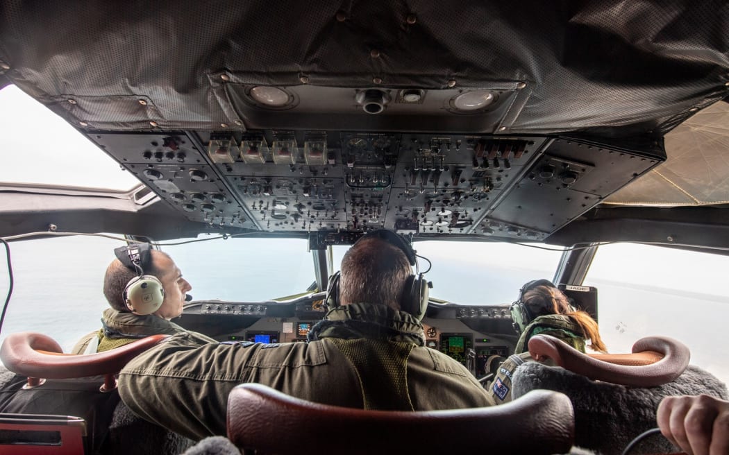 A P-3K2 Orion aircraft flies over an area of Tonga that shows the heavy ash fall from the recent volcanic eruption within the Tongan Islands.