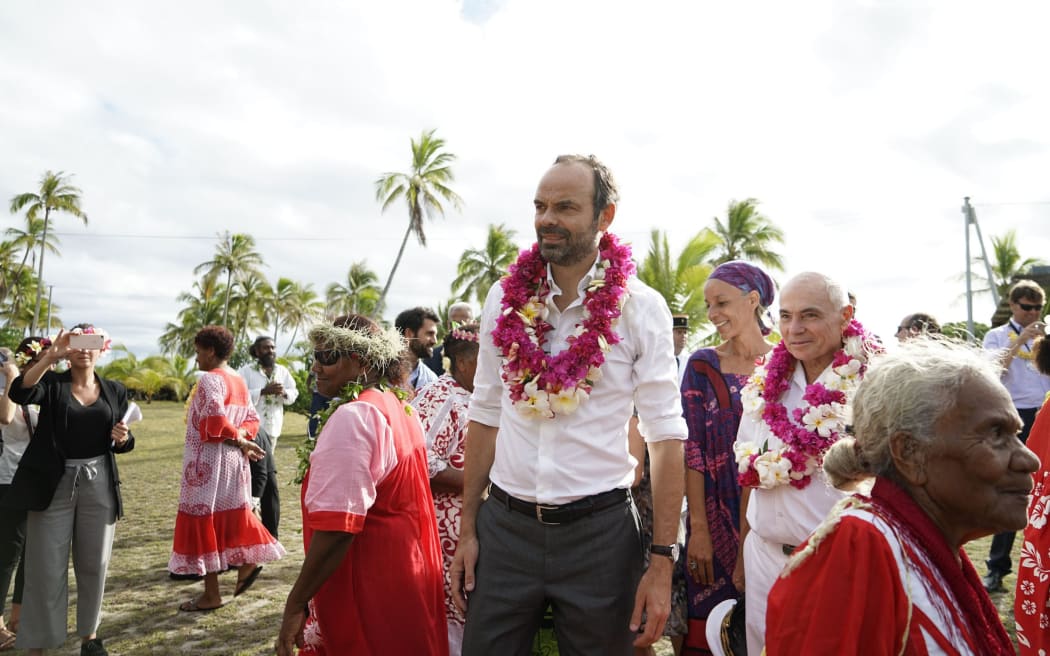French Prime Minister Edouard Philippe reacts after receiving a flower neklace during a welcoming ceremony at the Tiga chiefdom, on Tiga island on December 3, 2017. / AFP PHOTO / Fred Payet