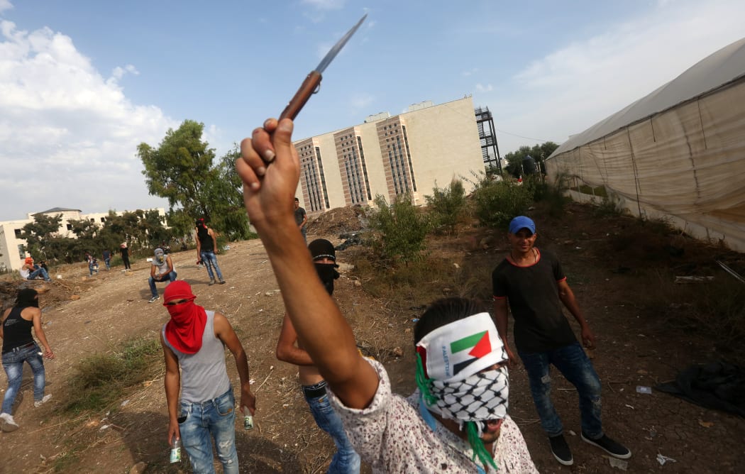 A Palestinian youth raises a knife during clashes with Israeli security forces (unseen) in the West Bank city of Tulkarem on October 18, 2015.