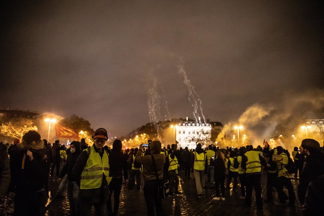 "Yellow vests" demonstrators wave Breton and French flags in front of the Arc de Triomphe, which was completely destroyed inside.