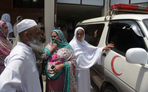 Relatives of a young Pakistani woman who died from injuries she suffered when set on fire stand by the ambulance carrying her body.