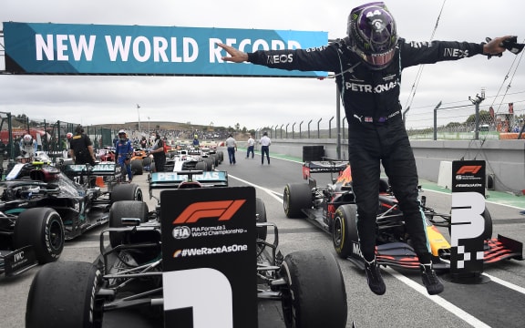 Mercedes' British driver Lewis Hamilton celebrates in the parc ferme after winning the Portuguese Grand Prix to become the most successful driver in Formula One history.