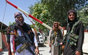Taliban fighters stand guard along a roadside near the Zanbaq Square in Kabul on 16 August.