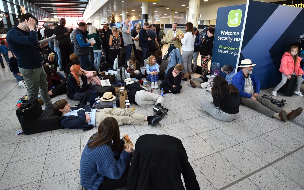 Passengers wait at Gatwick airport as police and the military try to locate two drones spotted near the runway.