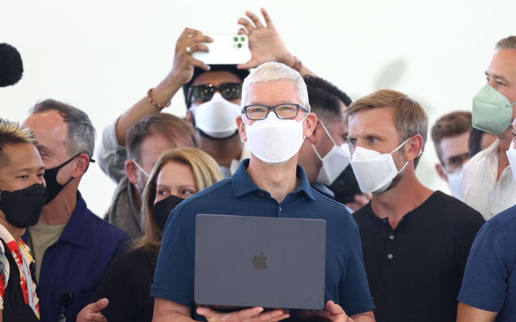Apple CEO'su Tim Cook (ortada), şirketin 6 Haziran 2022'deki yıllık Geliştiriciler Konferansı sırasında yeniden tasarlanmış bir MacBook Air dizüstü bilgisayarı tutuyor.