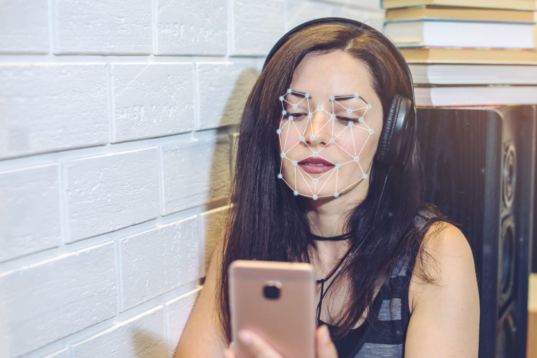 Biometric verification. Modern young woman with the phone. The concept of a new technology of face recognition on polygonal grid is constructed by the points of IT security and protection