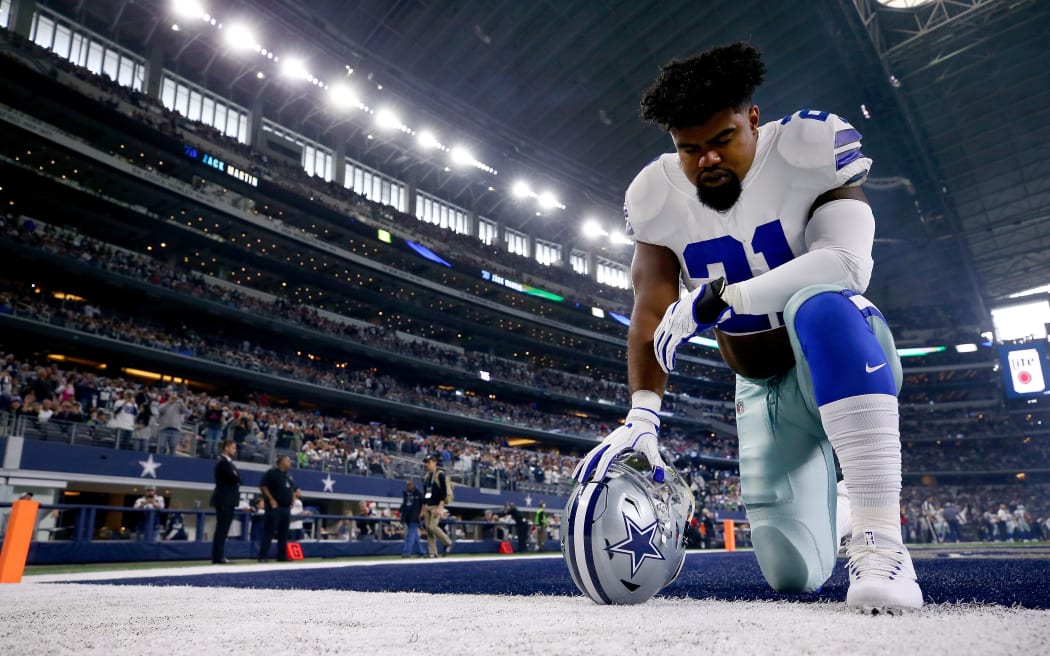 Ezekiel Elliott of the Dallas Cowboys kneels before a game at AT&T Stadium.