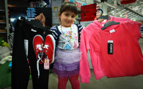 3 year old Elisha Jamal holding up $24.49 worth of clothes.