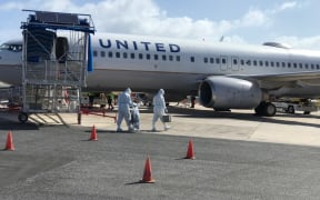 For the one flight per month now scheduled to the Marshall Islands, United Airlines Majuro workers don full-body personal protective gear to briefly enter the plane.