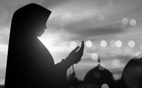 Silhouette of Muslim woman praying .